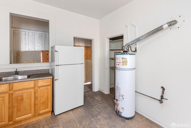 kitchen with dark countertops, water heater, freestanding refrigerator, and a sink