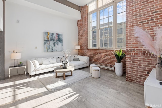 living area featuring brick wall, beamed ceiling, a towering ceiling, and hardwood / wood-style floors