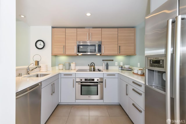 kitchen featuring appliances with stainless steel finishes, a sink, light countertops, light tile patterned floors, and recessed lighting