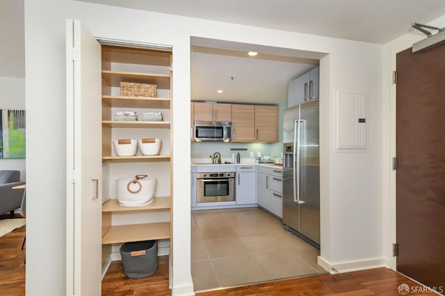 kitchen with appliances with stainless steel finishes, electric panel, light countertops, baseboards, and recessed lighting