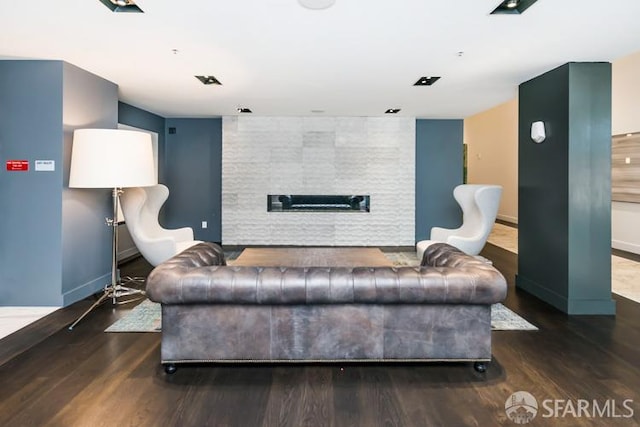 living room with baseboards, wood finished floors, and a tile fireplace