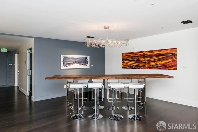 indoor dry bar featuring baseboards, wood finished floors, and a chandelier