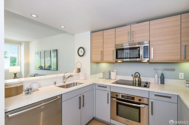kitchen with stainless steel appliances, a sink, gray cabinets, light countertops, and recessed lighting