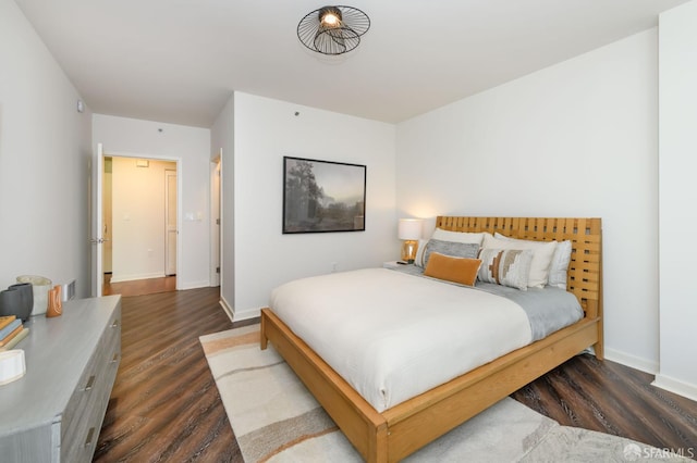 bedroom with dark wood-type flooring and baseboards
