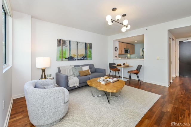 living room featuring dark wood-style floors, a chandelier, and baseboards