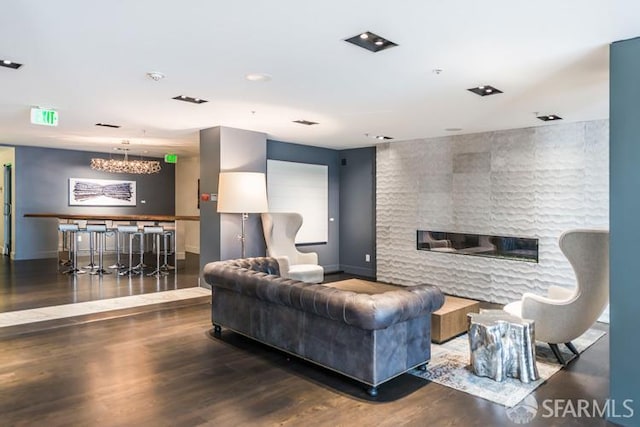 living area with wood finished floors, a chandelier, and a bar
