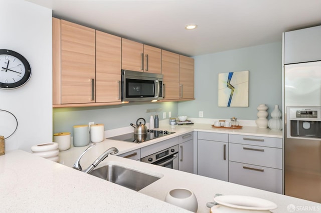 kitchen with appliances with stainless steel finishes, light countertops, a sink, and recessed lighting