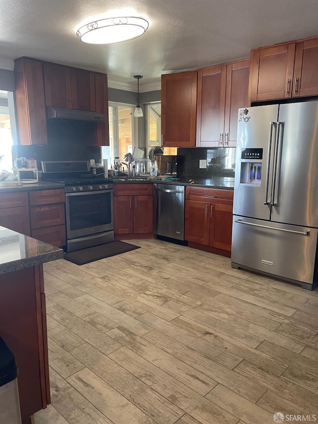 kitchen featuring decorative light fixtures, light hardwood / wood-style floors, appliances with stainless steel finishes, and tasteful backsplash