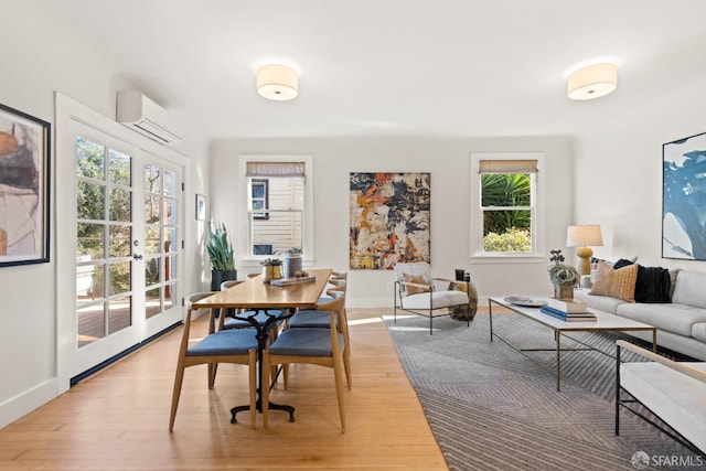 dining room with a wall mounted air conditioner, french doors, and light hardwood / wood-style flooring