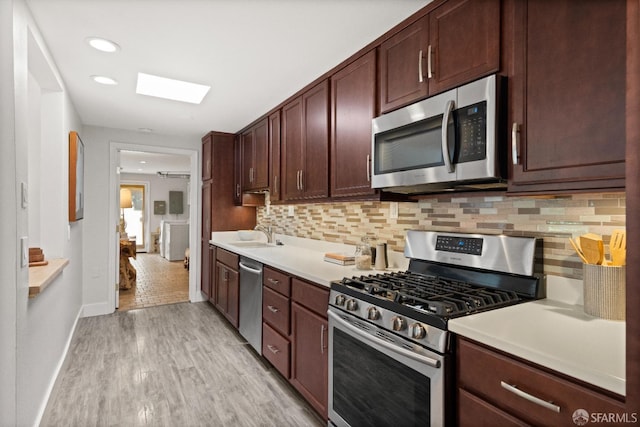 kitchen featuring decorative backsplash, stainless steel appliances, light hardwood / wood-style flooring, and sink