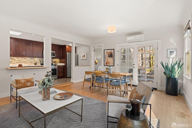 living room with light hardwood / wood-style floors, an AC wall unit, and french doors