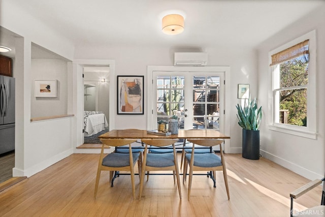 dining space featuring an AC wall unit, a wealth of natural light, and light hardwood / wood-style flooring