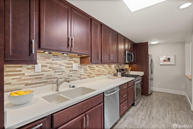 kitchen featuring backsplash, light hardwood / wood-style floors, sink, and stainless steel appliances