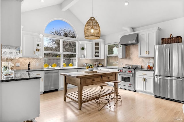 kitchen featuring pendant lighting, white cabinets, stainless steel appliances, and wall chimney exhaust hood