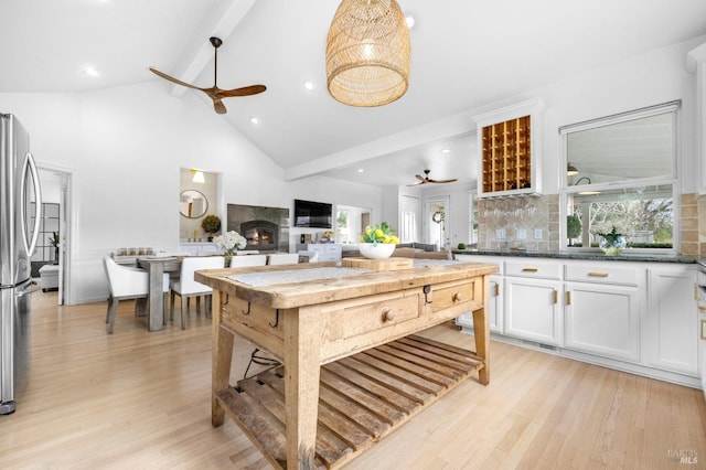 kitchen featuring ceiling fan, decorative backsplash, stainless steel refrigerator, beam ceiling, and white cabinets