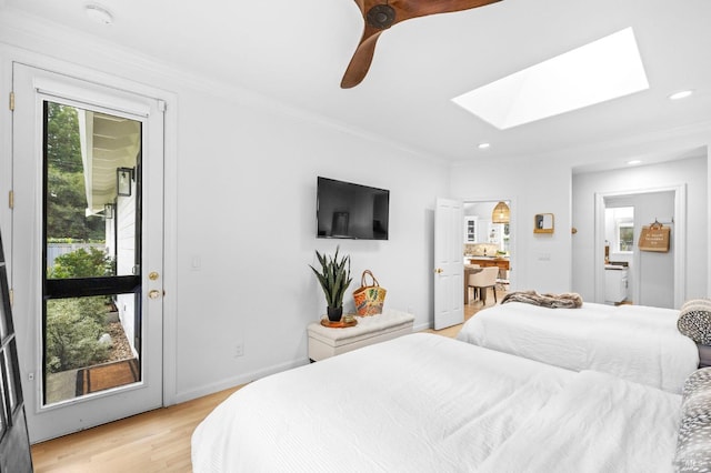 bedroom featuring ceiling fan, light hardwood / wood-style floors, ensuite bath, access to outside, and a skylight