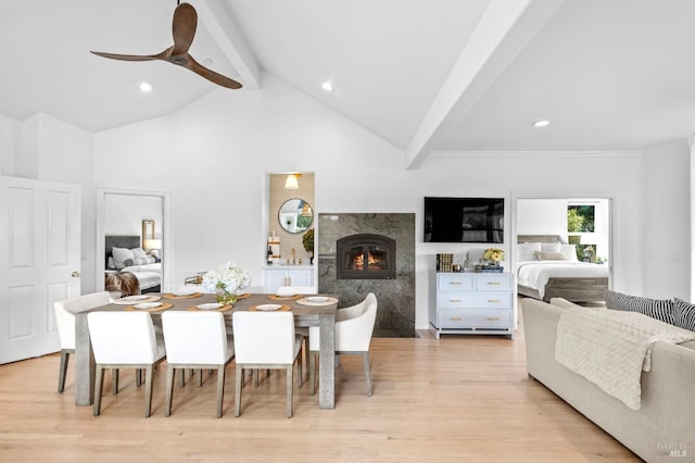 dining space with ceiling fan, a high end fireplace, light hardwood / wood-style flooring, and lofted ceiling with beams