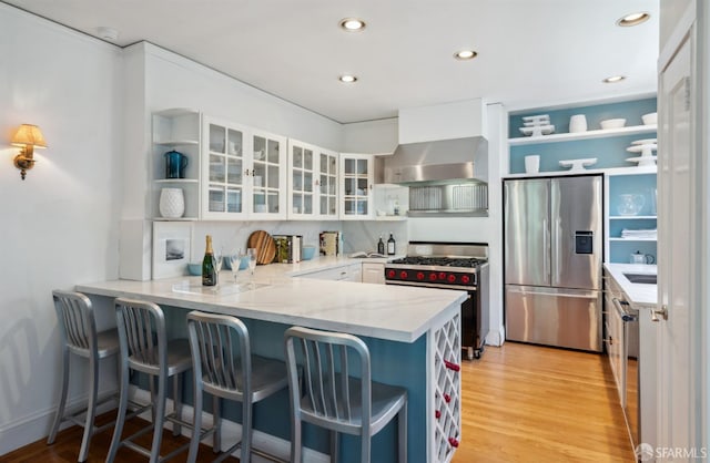 2932 Baker St, San Francisco, CA 94123 - kitchen featuring stainless steel appliances, open shelves, wall chimney exhaust hood, a peninsula, and white cabinetry
