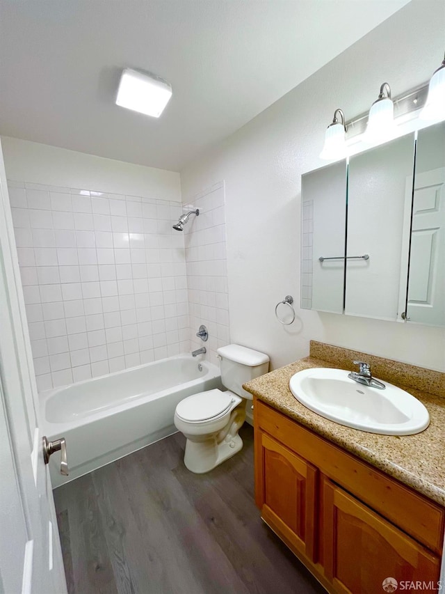 full bathroom featuring tiled shower / bath, vanity, wood-type flooring, and toilet