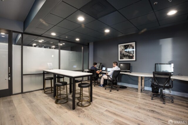 dining room featuring a drop ceiling, light hardwood / wood-style floors, and built in desk