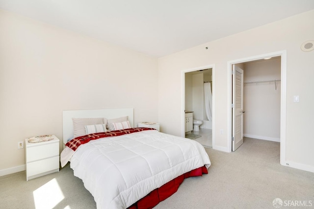 carpeted bedroom featuring a walk in closet, ensuite bath, and a closet