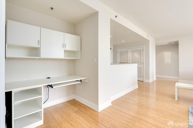 kitchen featuring white cabinets, light hardwood / wood-style floors, and built in desk