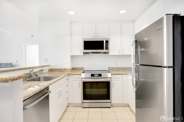 kitchen featuring sink, light tile patterned floors, appliances with stainless steel finishes, white cabinetry, and kitchen peninsula