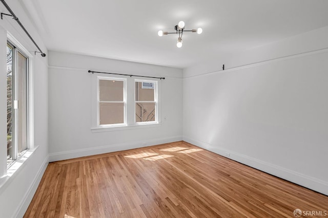 empty room featuring a wealth of natural light, baseboards, and wood finished floors