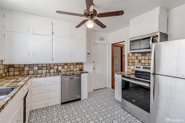 kitchen with white cabinetry, tile counters, a ceiling fan, and stainless steel appliances