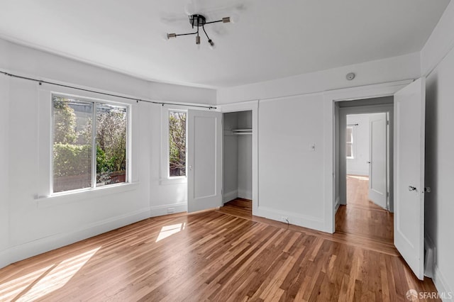 unfurnished bedroom with a closet, baseboards, and wood finished floors