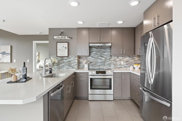 kitchen with kitchen peninsula, tasteful backsplash, stainless steel appliances, sink, and light tile patterned floors