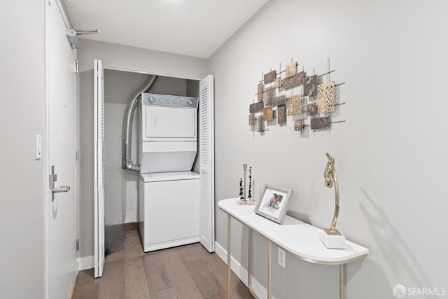 corridor with wood-type flooring and stacked washer and clothes dryer