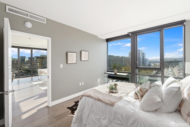 bedroom with floor to ceiling windows and hardwood / wood-style flooring