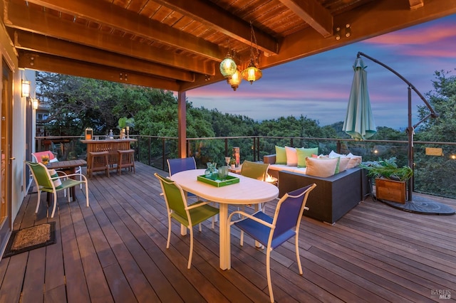 deck at dusk with outdoor dining area and outdoor lounge area