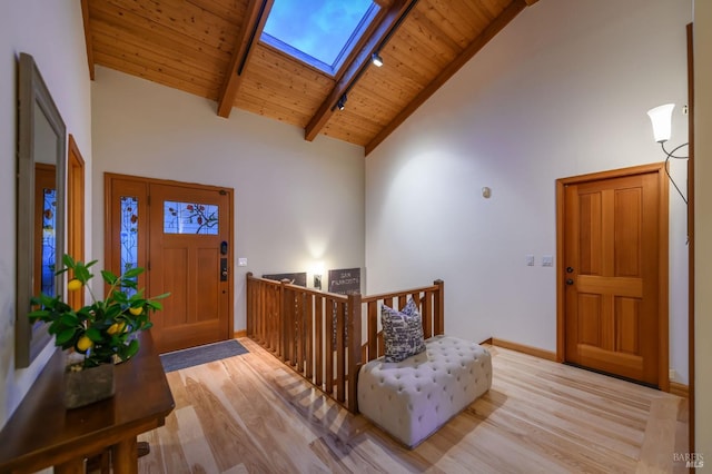 entryway with a skylight, wood finished floors, high vaulted ceiling, wooden ceiling, and beamed ceiling