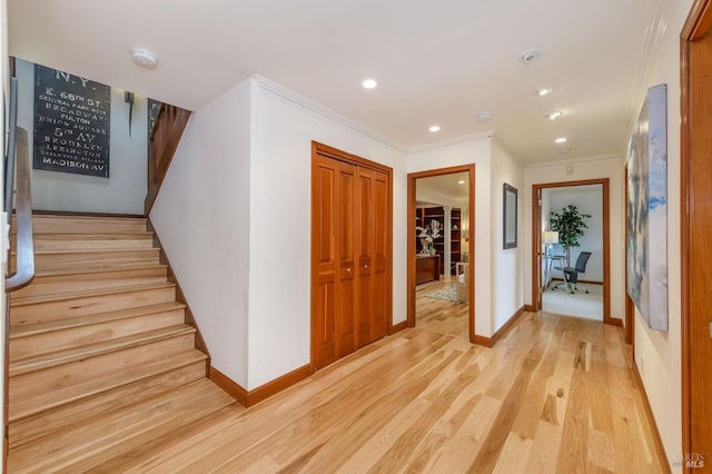 corridor featuring crown molding, stairway, baseboards, light wood finished floors, and recessed lighting