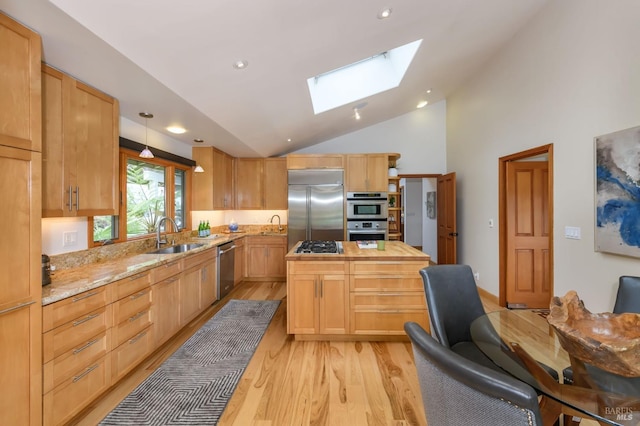 kitchen featuring a skylight, appliances with stainless steel finishes, light wood-type flooring, a sink, and light brown cabinets