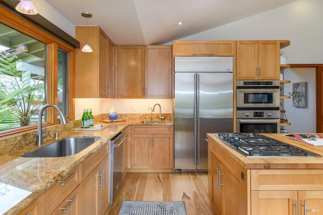 kitchen with light brown cabinetry, light wood-type flooring, a sink, appliances with stainless steel finishes, and vaulted ceiling