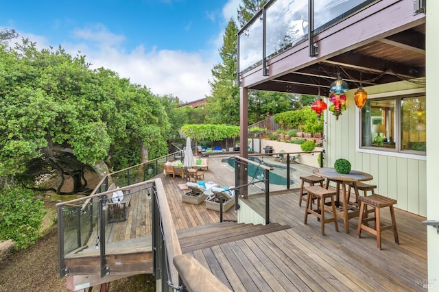 wooden terrace with outdoor dining area and a fenced in pool