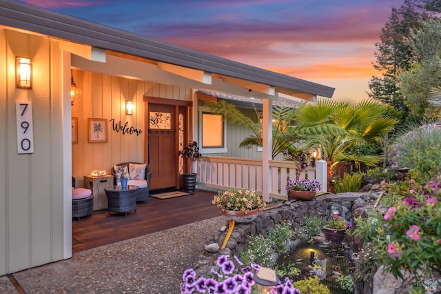 exterior entry at dusk featuring a porch and board and batten siding