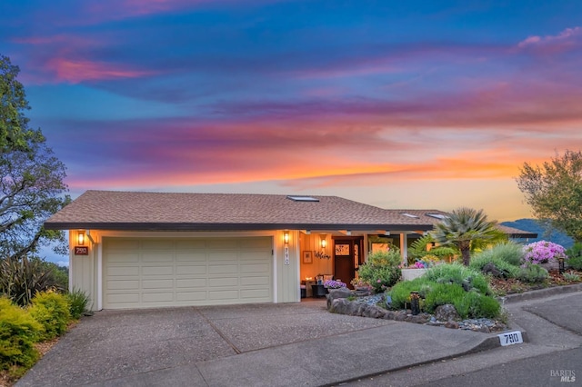 ranch-style home with a garage and aphalt driveway