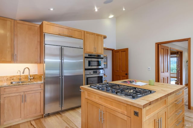 kitchen featuring butcher block countertops, a sink, light brown cabinets, and stainless steel appliances