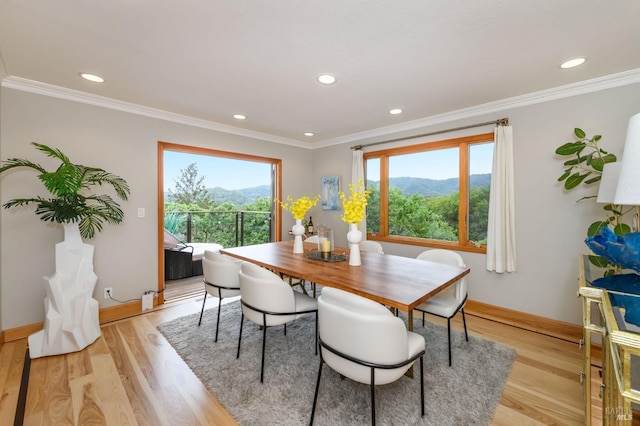 dining space with crown molding, baseboards, a mountain view, and light wood finished floors