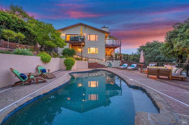 pool at dusk featuring a fenced in pool, fence, an outdoor hangout area, a patio, and stairs