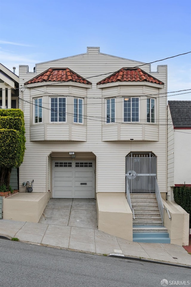 multi unit property with driveway, a garage, and a tiled roof