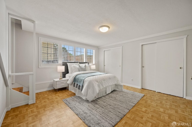 bedroom with a textured ceiling, multiple closets, and baseboards