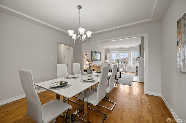 dining room featuring baseboards, wood finished floors, and a notable chandelier