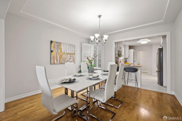 dining area featuring baseboards, light wood-type flooring, and a notable chandelier