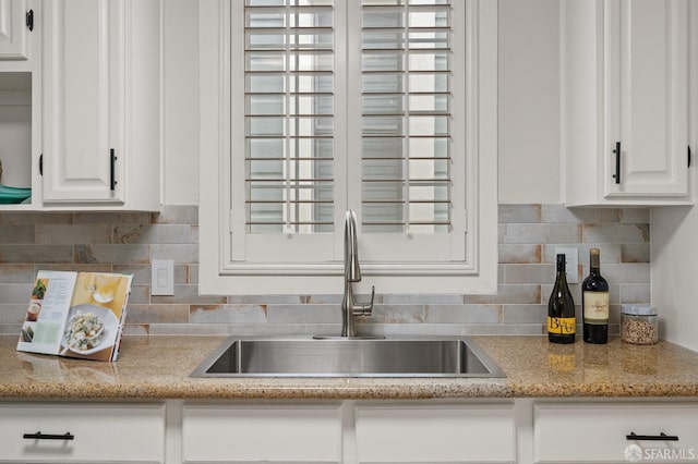 kitchen featuring plenty of natural light, a sink, white cabinets, and tasteful backsplash
