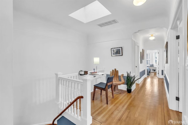 hallway with a skylight and hardwood / wood-style flooring